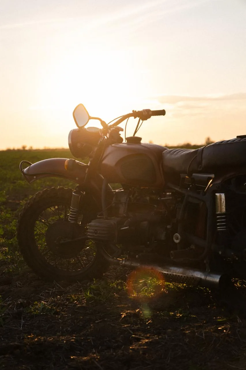 Vintage motorcycle silhouetted against a field sunset