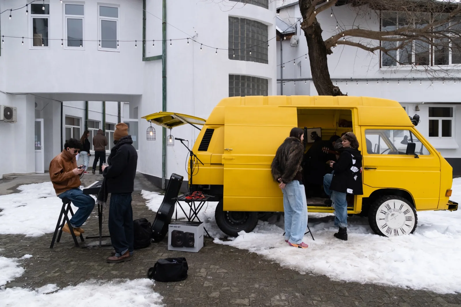 Yellow van hosting a small live music event in a courtyard